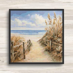 Könnte beinhalten: Ein gerahmtes Kreuzstichbild einer Strandszene. Ein Holzsteg führt zu einem Sandstrand und Ozean unter blauem Himmel mit flauschigen Wolken. Hohe Gräser und Holzzäune säumen den Weg und schaffen eine ruhige Küstenlandschaft.