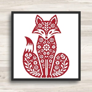 Pode incluir: Um padrão de ponto cruz emoldurado quadrado apresentando a silhueta de uma raposa em vermelho escuro sobre um fundo branco. O corpo da raposa é preenchido com intrincados motivos florais e de folhas brancas, criando um design detalhado e simétrico.