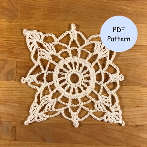 Op de afbeelding: Een wit gehaakt sneeuwvlokpatroon, met een PDF-patroonetiket in de rechterbovenhoek.