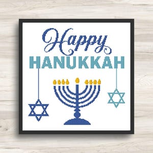 May include: A cross-stitch pattern featuring the text Happy HANUKKAH in blue and light blue. Below the text is a blue menorah with yellow flames, flanked by two blue Star of David symbols hanging from vertical lines, all within a black frame.