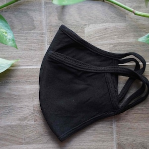 Può includere: Maschera facciale in cotone nero con cinturini regolabili. La maschera è composta da un doppio strato di tessuto ed è progettata per adattarsi comodamente al naso e alla bocca.