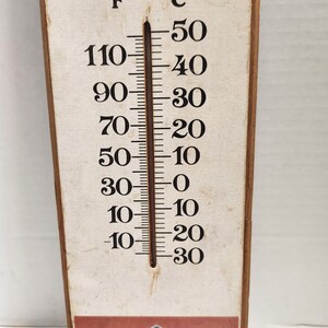 May include: A vintage thermometer with a beige background and black markings. The temperature scale is in Fahrenheit and Celsius. The thermometer reads approximately 10 degrees Fahrenheit and -12 degrees Celsius.