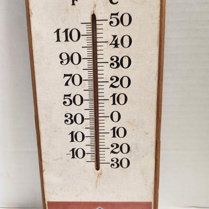 May include: A vintage thermometer with a beige background and black markings. The temperature scale is in Fahrenheit and Celsius. The thermometer reads approximately 10 degrees Fahrenheit and -12 degrees Celsius.