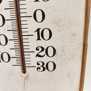May include: Close-up of a vintage thermometer with black numbers and markings on a cream-colored background. The temperature scale ranges from 0 to 30, with a brown column indicating the current temperature reading.