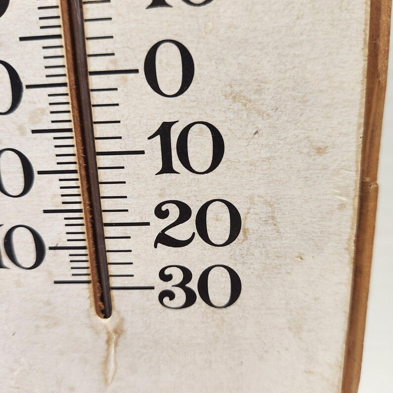 May include: Close-up of a vintage thermometer with black numbers and markings on a cream-colored background. The temperature scale ranges from 0 to 30, with a brown column indicating the current temperature reading.