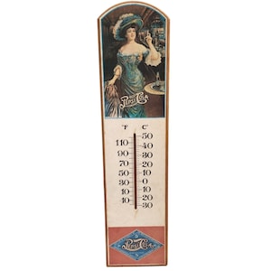 May include: Vintage Pepsi Cola thermometer with a painted image of a woman in a blue dress. The thermometer displays Fahrenheit and Celsius scales, with the Pepsi Cola logo at the bottom. The thermometer measures approximately 18 inches in height.
