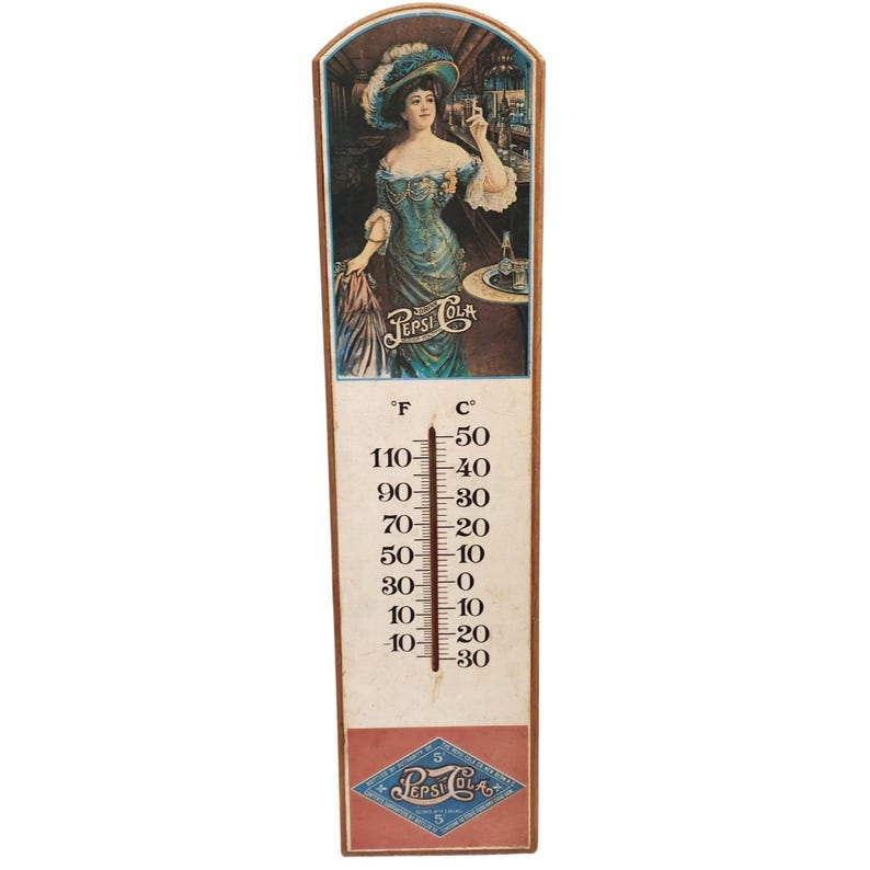 May include: Vintage Pepsi Cola thermometer with a painted image of a woman in a blue dress. The thermometer displays Fahrenheit and Celsius scales, with the Pepsi Cola logo at the bottom. The thermometer measures approximately 18 inches in height.