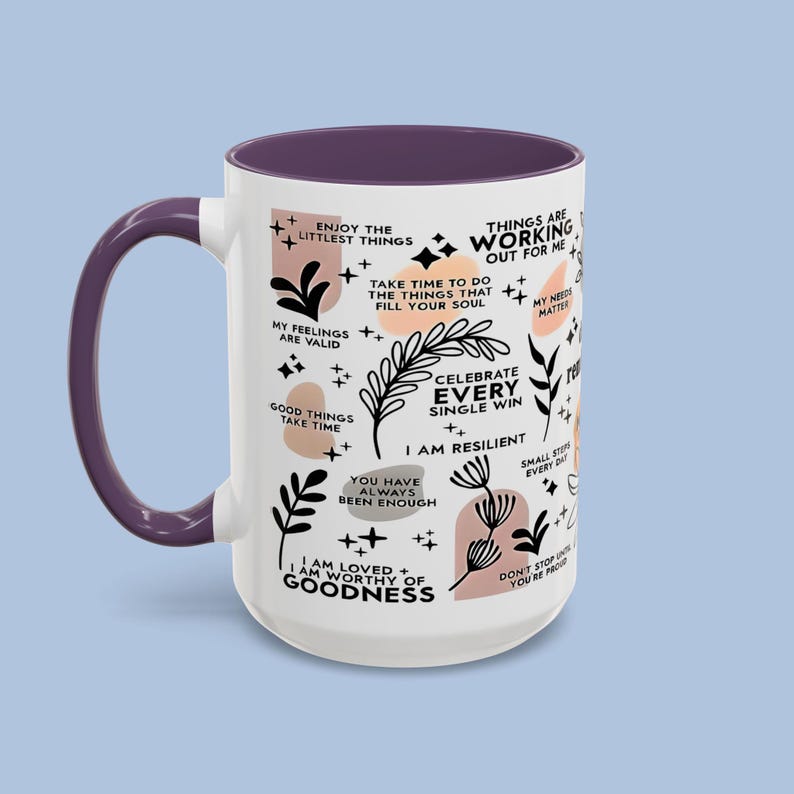 Puede incluir: Una taza de cer&aacute;mica blanca con interior y asa morados. La taza est&aacute; decorada con frases inspiradoras e ilustraciones bot&aacute;nicas en negro y melocot&oacute;n. El texto incluye "Disfruta de las peque&ntilde;as cosas" y "Celebra cada victoria".
