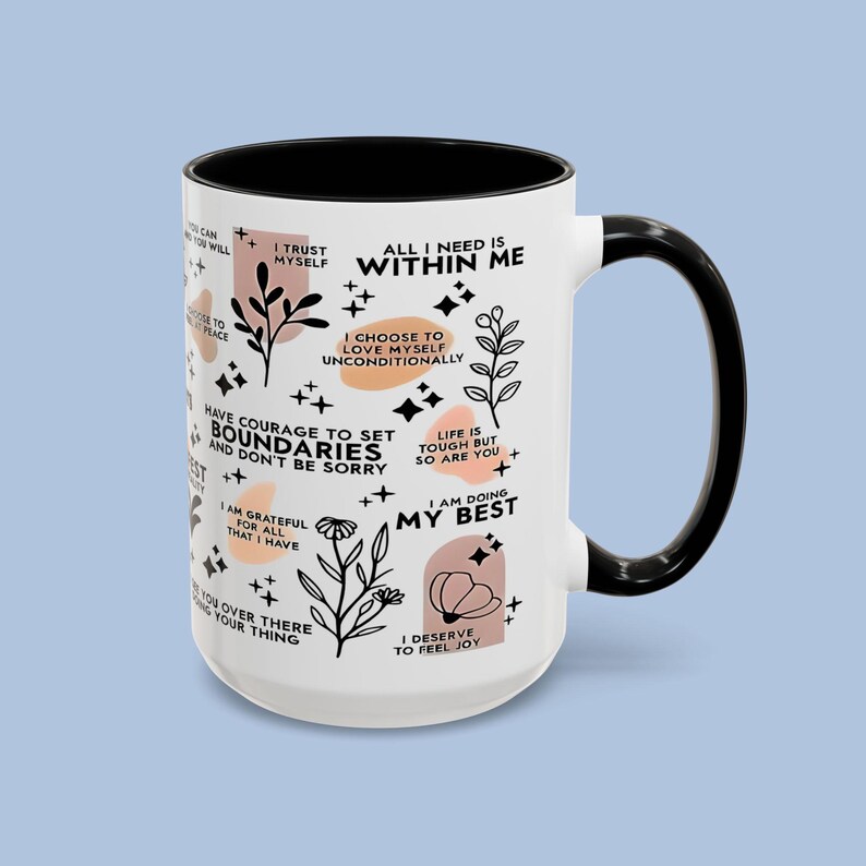 Puede incluir: Taza de cer&aacute;mica blanca con interior, asa y borde negros. La taza presenta texto inspirador e ilustraciones florales en negro y melocot&oacute;n. El texto incluye frases como "Conf&iacute;o en m&iacute; mismo" y "Estoy haciendo lo mejor que puedo."