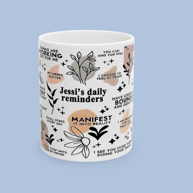 Puede incluir: Taza de cer&aacute;mica blanca con el texto "Jessi's daily reminders" y frases inspiradoras. La taza presenta dise&ntilde;os florales y geom&eacute;tricos en negro, beige y melocot&oacute;n. La taza es un art&iacute;culo motivacional.