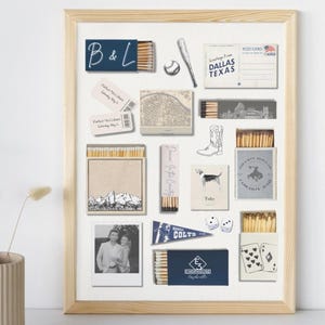 May include: A framed collage featuring various vintage-style items. Includes a baseball, postcards, a map, and matchboxes with illustrations and text. The text "B&L" is visible, along with other text and images. The frame is a light wood color.