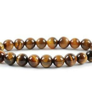 Puede incluir: Un brazalete de cuentas de ojo de tigre marrón y dorado. El brazalete está hecho de cuentas redondas y tiene un diseño simple.