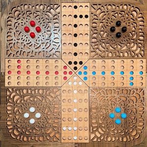 Puede incluir: Un juego de mesa de madera con un borde decorativo tallado. El tablero del juego está dividido en cuatro cuadrantes, cada uno con un color diferente de piezas: rojo, negro, blanco y azul. El tablero es de color madera clara con detalles tallados en marrón oscuro.