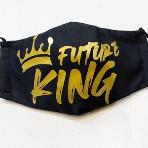 May include: Black face mask with gold elastic straps and a gold crown and the words "Future King" printed on the front.