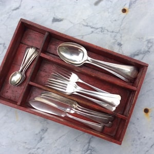 May include: A wooden cutlery tray with compartments for spoons, forks, and knives. The tray is filled with silver cutlery, including spoons, forks, and a butter knife.