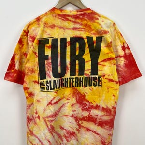 May include: A tie-dye t-shirt in shades of red and yellow with the text "Fury in the Slaughterhouse" printed on the back.