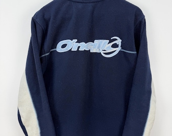Könnte beinhalten: Eine marineblaue Fleecejacke mit Stehkragen und durchgehendem Reißverschluss. Auf der Rückseite befindet sich ein großes, hellblau gesticktes O'Neill-Logo. Die Ärmel haben breite cremefarbene Einsätze an den Außenseiten mit hellblauen Nähten.