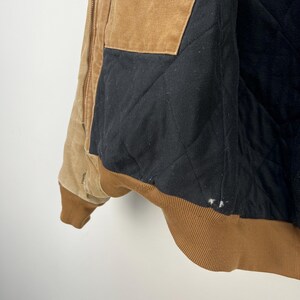 Puede incluir: Chaqueta de trabajo marr&oacute;n y beige con forro acolchado negro. La chaqueta tiene cuello y pu&ntilde;os de pana marr&oacute;n. El interior es negro y acolchado. Cierre de cremallera y varios bolsillos.