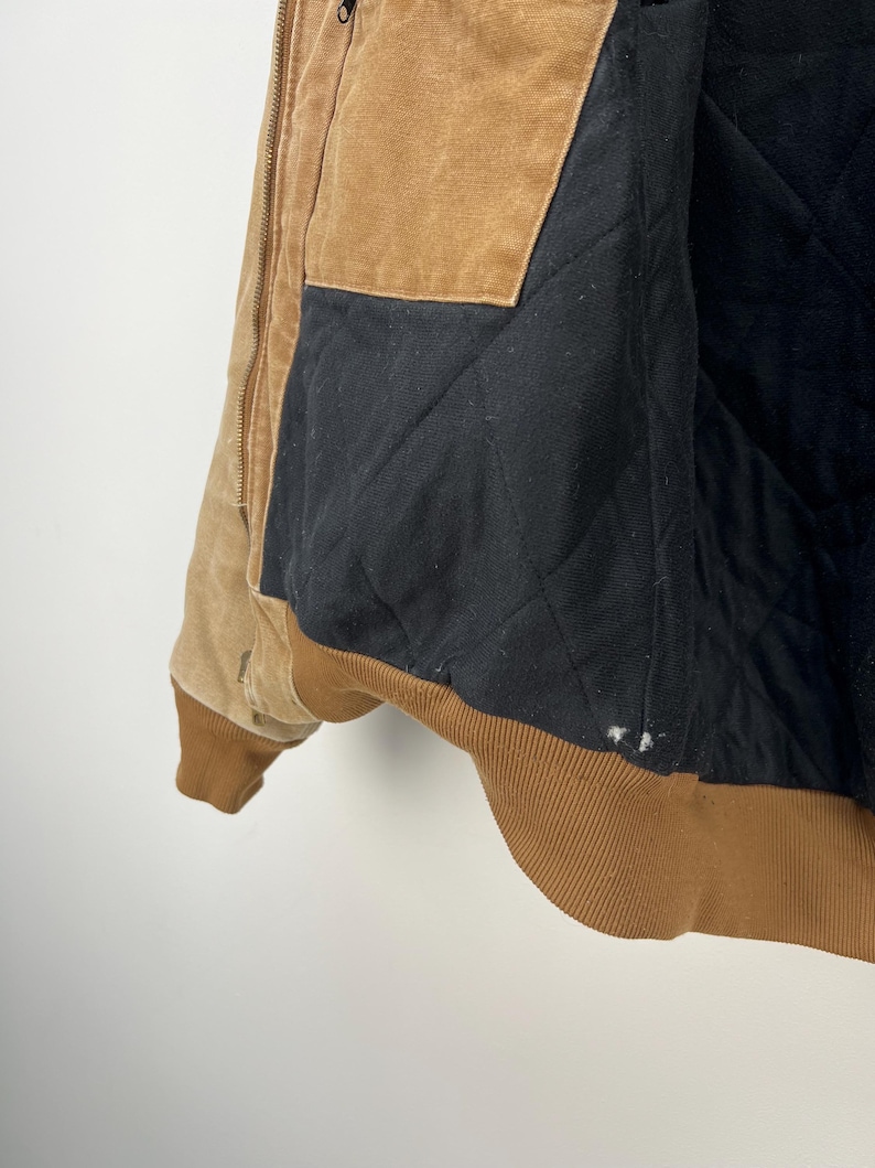 Puede incluir: Chaqueta de trabajo marr&oacute;n y beige con forro acolchado negro. La chaqueta tiene cuello y pu&ntilde;os de pana marr&oacute;n. El interior es negro y acolchado. Cierre de cremallera y varios bolsillos.