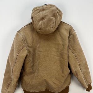 Puede incluir: Chaqueta con capucha marr&oacute;n con dobladillo y pu&ntilde;os acanalados marrones. La chaqueta tiene un forro acolchado y una cremallera completa. Fabricada con un tejido resistente de estilo workwear.
