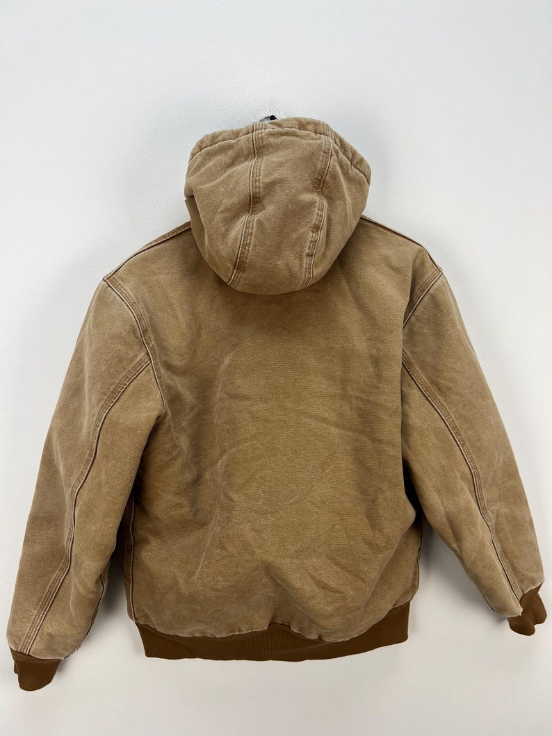 Puede incluir: Chaqueta con capucha marr&oacute;n con dobladillo y pu&ntilde;os acanalados marrones. La chaqueta tiene un forro acolchado y una cremallera completa. Fabricada con un tejido resistente de estilo workwear.