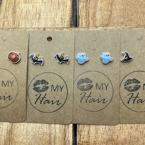 May include: Four sets of Halloween-themed stud earrings on brown card stock with the text "MY Hair" printed on each card. The earrings feature a pumpkin, a bat, a ghost, and a witch's hat.