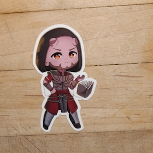 Puede incluir: Una pegatina de un personaje de estilo chibi de piel rosa, con cabello oscuro, que lleva una armadura roja y dorada, sosteniendo un libro. El personaje tiene una expresión seria y mira hacia la derecha.
