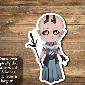 May include: A sticker featuring a cartoon character with pale skin, black markings on the head, and dark eye makeup. The character wears a blue and black outfit and holds a staff. The text on the sticker reads: "Dimensions: typically the height or width is 2.8 inches whichever is largest."