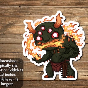 May include: A sticker featuring a cartoon demon with multiple eyes, horns, and flames. The demon is dark green with red eyes and orange flames. The text on the sticker reads: "Dimensions: typically the height or width is 2.8 inches whichever is largest."