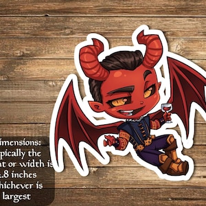 May include: A red and black cartoon sticker of a devil with horns and wings holding a glass of wine. The sticker is approximately 2.8 inches in size.