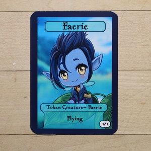 May include: A blue and green fantasy creature card with the text "Faerie" in a white box. The card is a token creature with the text "Token Creature - Faerie" and "Flying". The card has a power and toughness of 1/1.