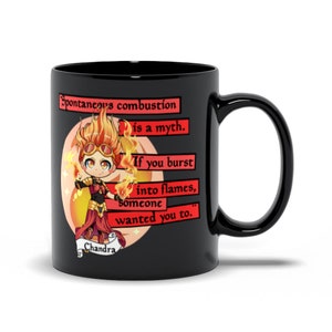 Puede incluir: Taza de café negra con una ilustración roja y naranja de un personaje de dibujos animados con cabello de fuego y una cita sobre la combustión espontánea. La cita dice "La combustión espontánea es un mito. Si estallas en llamas, alguien lo quiso." El nombre del personaje es "Chandra".