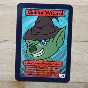 May include: A green goblin wizard with a brown pointed hat and blue eyes. The card reads "Goblin Wizard" and "Token Creature - Goblin Wizard". The card text reads "Prowess (Whenever you cast a noncreature spell, this creature gets +1/+1 until end of turn. 1/1".