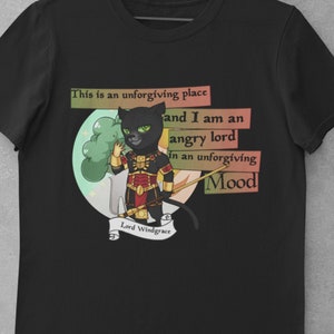Puede incluir: Camiseta negra con un personaje de gato de dibujos animados con armadura y un bastón. El texto en la camiseta dice: "Este es un lugar implacable y soy un señor enfadado en un estado de ánimo implacable". El personaje está etiquetado como "Lord Windgrace".