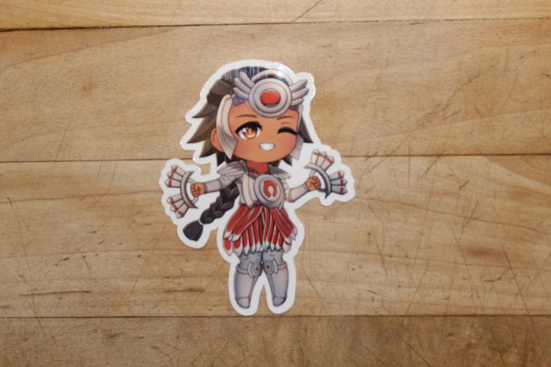 Pode incluir: Um adesivo branco com uma ilustra&ccedil;&atilde;o de desenho animado de uma personagem feminina com cabelo castanho, vestindo uma roupa branca e vermelha com uma faixa de cabe&ccedil;a vermelha e um cocar de penas brancas e vermelhas. A personagem est&aacute; piscando e segurando dois leques de penas brancas e vermelhas.