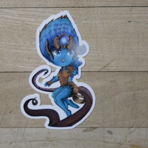 May include: A blue and brown cartoon sticker of a female character with a long tail and a blue gem on her forehead.