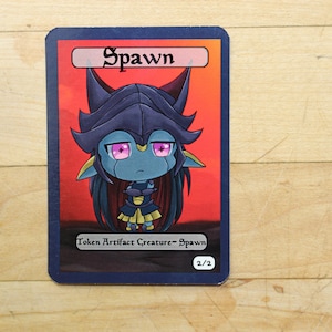 Może przedstawiać: Niebieska i fioletowa kreskówkowa istota z różowymi oczami na czerwonym tle. Karta zawiera napis "Spawn" i "Żeton Artefaktu Istota - Spawn 2/2".