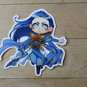 May include: A blue and gold anime-style sticker of a female character with long blue hair and a flowing blue robe. The character has large blue eyes and a surprised expression.