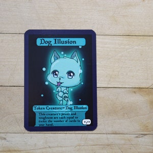 May include: A blue and black Magic: The Gathering card with a light blue dog illustration. The card text reads "Dog Illusion" and "Token Creature - Dog Illusion". The card text continues: "This creature's power and toughness are each equal to twice the number of cards in your hand."