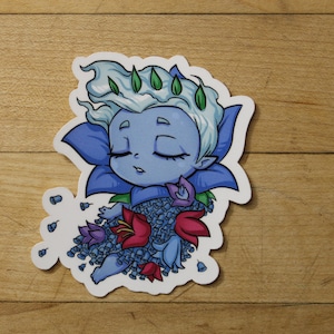 May include: A blue and purple sticker featuring a cartoon character with closed eyes, surrounded by blue and red flowers. The character has white hair and a crown of green leaves.