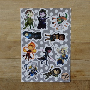 Puede incluir: Una hoja de pegatinas con varios personajes en estilo chibi. Los personajes están dibujados en estilo de dibujos animados y todos visten diferentes atuendos. Las pegatinas están impresas sobre un fondo blanco con lunares grises. El texto "Mega-Chibi" está impreso en la esquina inferior derecha.