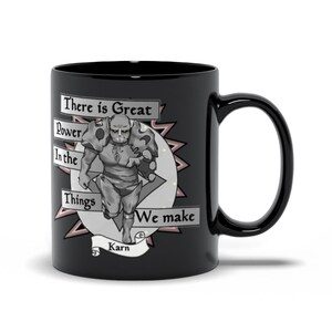 May include: Black ceramic mug with a white graphic of a character in armor. The text on the mug reads "There is Great Power In the Things We make Karn".