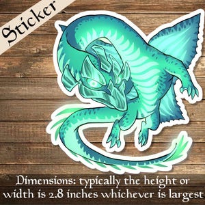 Puede incluir: Una pegatina de dragón azul verdoso y verde con un contorno blanco. El dragón tiene una cabeza puntiaguda y está enroscado con la cola en la boca. La pegatina mide aproximadamente 2,8 pulgadas.