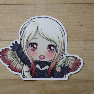 May include: A sticker featuring a cartoon illustration of a girl with blonde hair and red and white wings. She is wearing a black and blue outfit and has a surprised expression on her face.