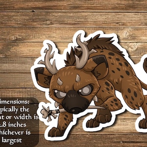 Puede incluir: Una pegatina de dibujos animados de una hiena marrón y negra con cuernos, sosteniendo un hueso en la boca. La hiena tiene una expresión feroz y dientes afilados. La pegatina mide 2,8 pulgadas.