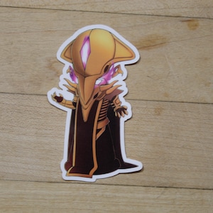 May include: A gold and purple cartoon character sticker with a large head and a long, flowing robe. The character has a large, pointed head with a single eye and a long, thin beak.