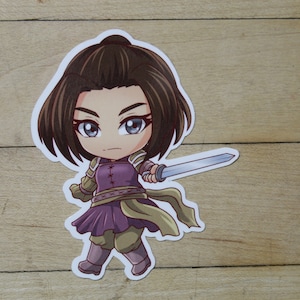 May include: A cartoon sticker of a female character with brown hair, wearing a purple and brown outfit, holding a silver sword. The character has a serious expression on her face.