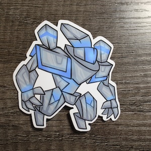 May include: A gray and blue robot sticker with a geometric design. The robot has a large head with a blue visor and a body with sharp edges.