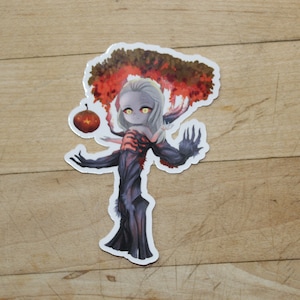 May include: A sticker featuring a cartoon character with long white hair and a dark, tree-like body. The character is holding a red apple and is surrounded by a red and orange tree with leaves.