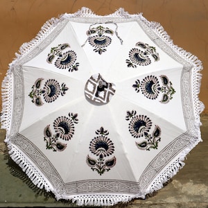 Puede incluir: Sombrilla de patio de algodón blanco con borde de flecos y estampado floral en tonos azules, verdes y grises.